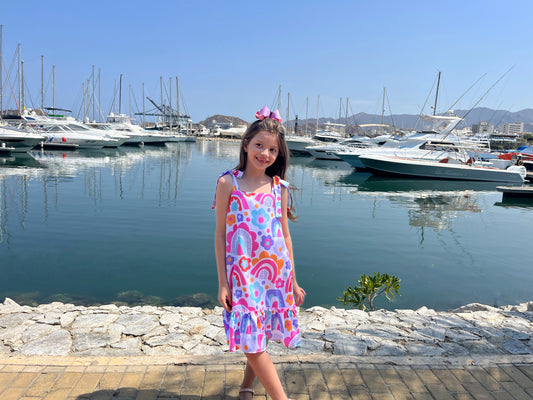 Niña usando un vestido de flores de colores y arcoiris en una marina