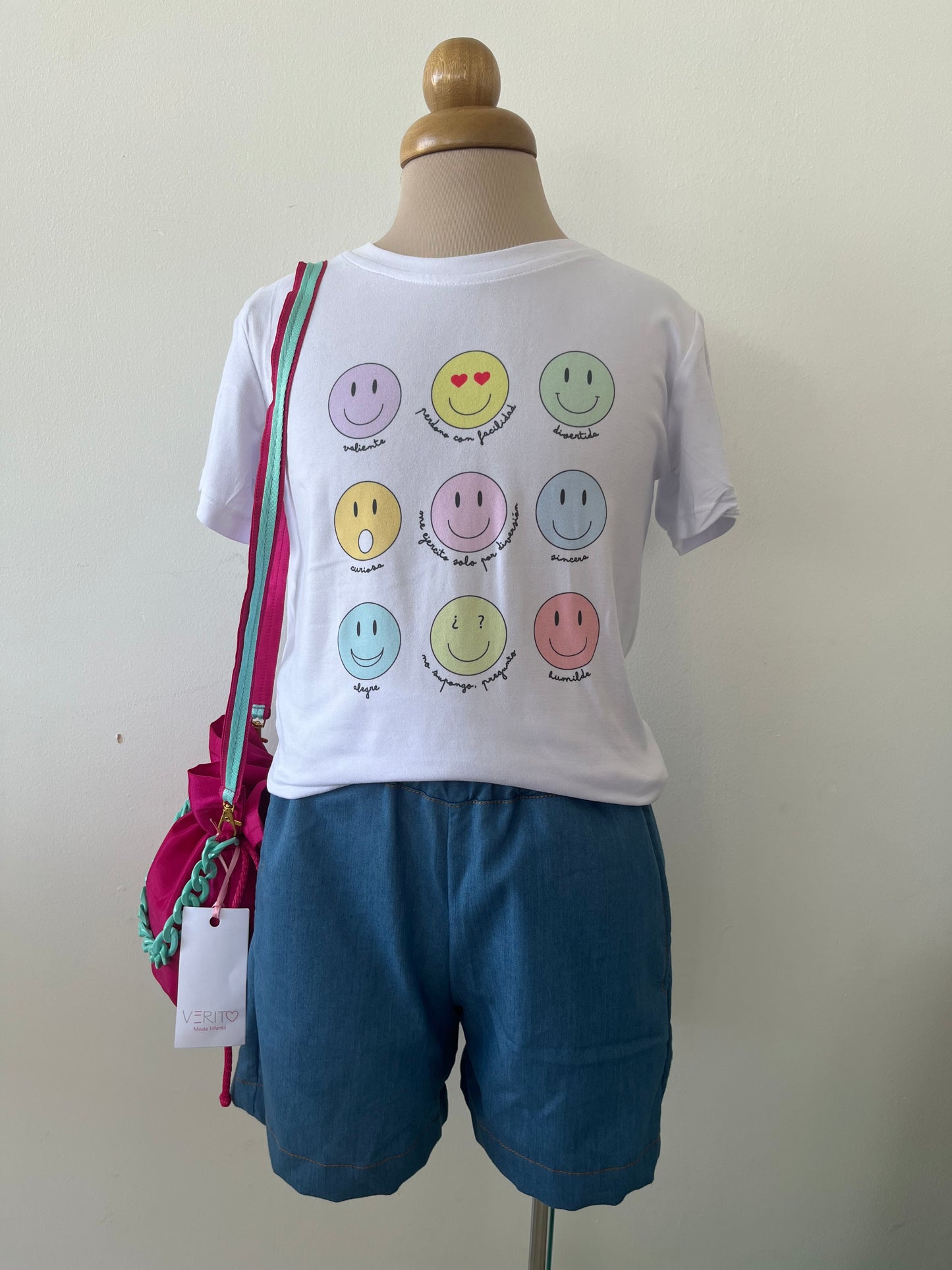 outfit de short en tela tipo denim liviano con camiseta de caritas felices de varios colores y mochila fucsia con turquesa