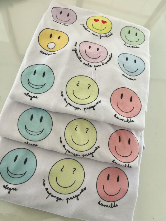 tres camisetas dobladas con el diseño de caritas felices de colores